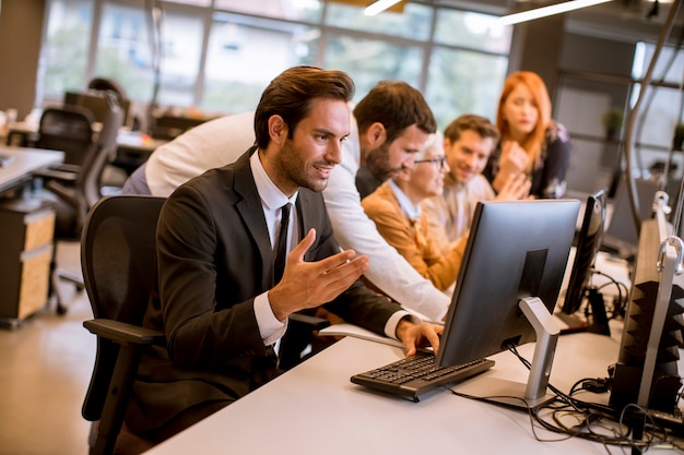 De jonge professionele zakenman gebruikt laptop voor het werk op kantoor