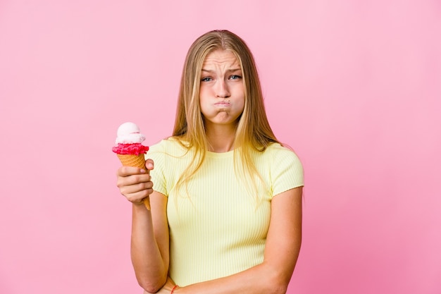 De jonge russische vrouw die een geïsoleerde roomijs eet blaast wangen, heeft vermoeide uitdrukking. Gezichtsuitdrukking concept.