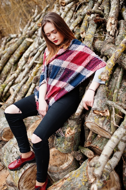 De jonge slijtage van het hipstermeisje op deken tegen houten stompen op hout.