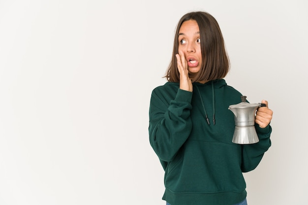 De jonge spaanse vrouw die een koffiezetapparaat houdt zegt een geheim heet remmend nieuws en kijkt opzij