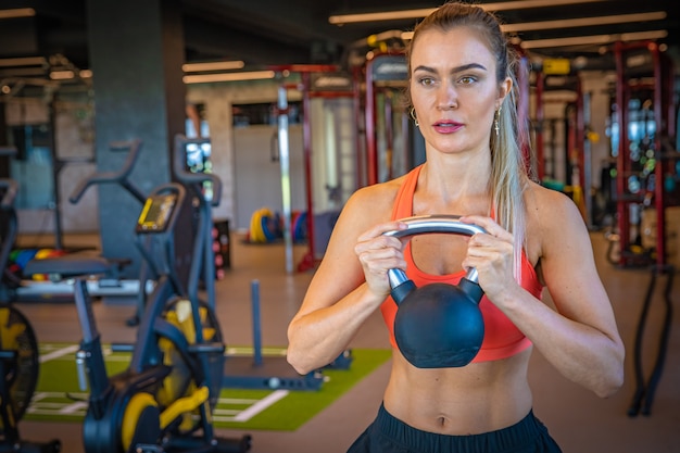 De jonge sportieve vrouw versterkt met domoren in gymnastiek