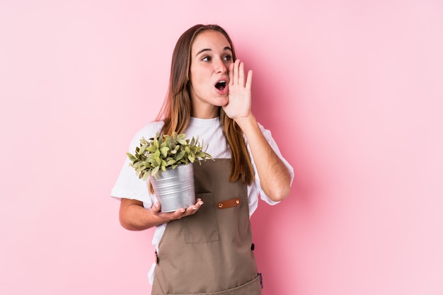 De jonge tuinman Kaukasische vrouw isoleerde schreeuwend en houdend palm dichtbij geopende mond.