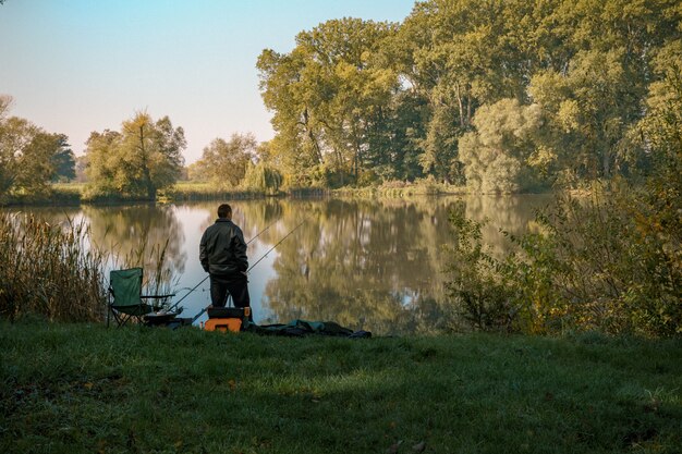 De jonge visser bij meer vangt vissen tijdens de zomertijd