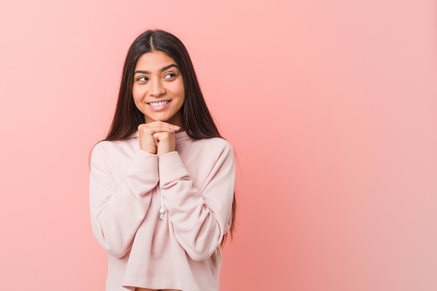 De jonge vrij Arabische vrouw die een toevallige sportlook draagt houdt handen onder kin