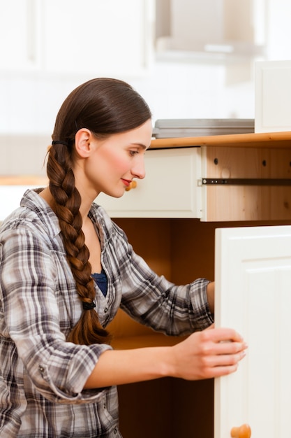 De jonge vrouw assembleert een kast