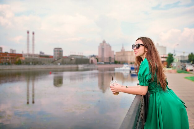 De jonge vrouw bekijkt de zonsondergang over een rivier in de stad