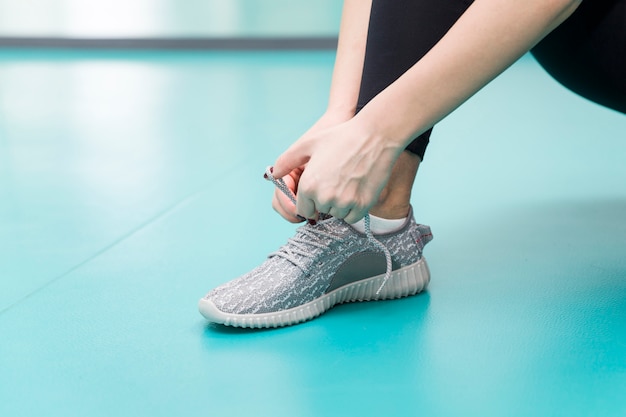 De jonge vrouw bindt de veters op de schoenen in de gymnastiek