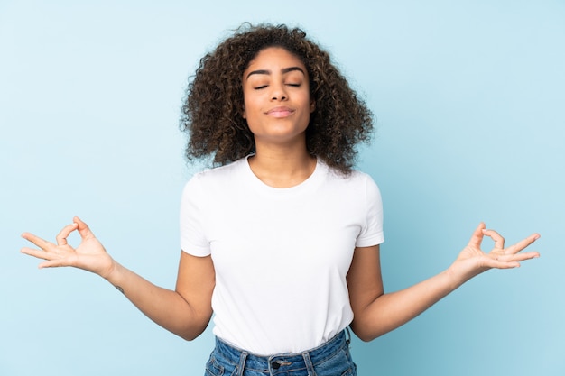 De jonge vrouw die op blauwe muur in zen wordt geïsoleerd stelt