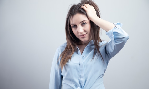 De jonge vrouw dient haar op grijze achtergrond in