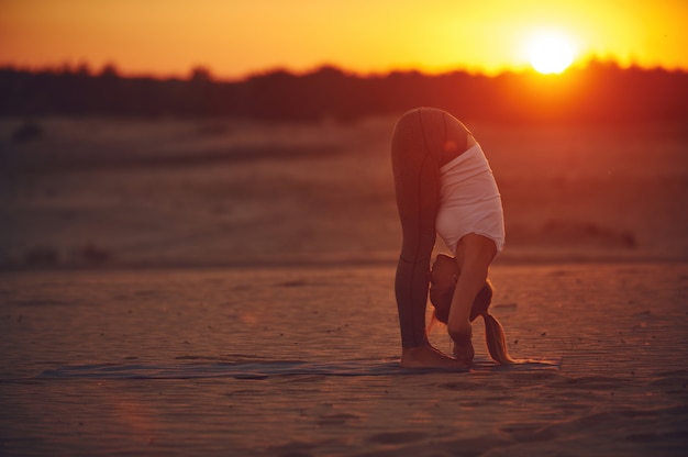 De jonge vrouw doet yogaasana Uttanasana