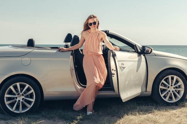 De jonge vrouw drijft een auto op het strand