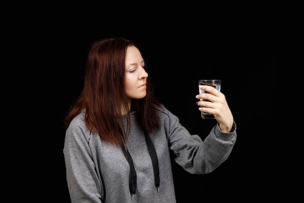 De jonge vrouw drinkt zuiver schoon water uit het glas