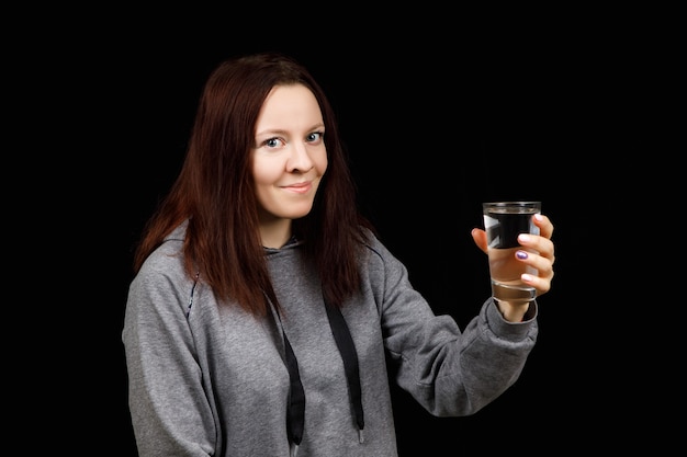 De jonge vrouw drinkt zuiver schoon water uit het glas