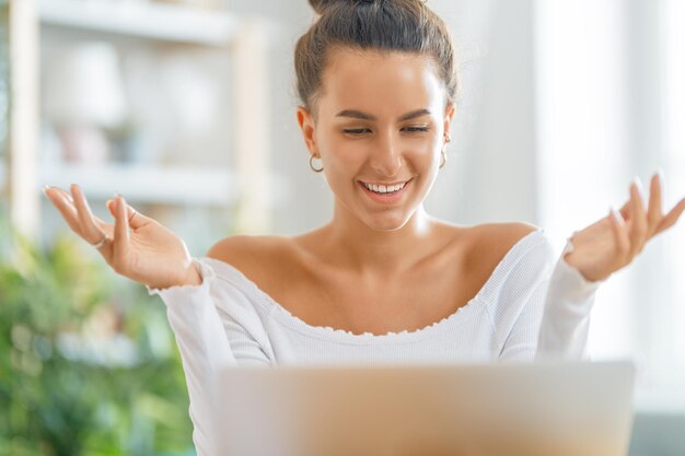 De jonge vrouw gebruikt laptop. Grappig meisje dat plezier heeft om thuis te blijven.