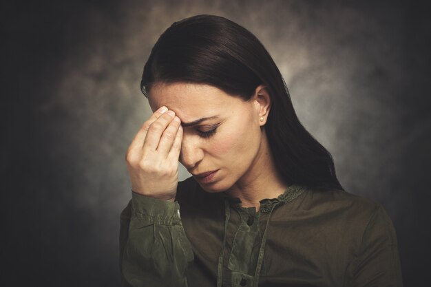 De jonge vrouw heeft hoofdpijn op een grungy achtergrond