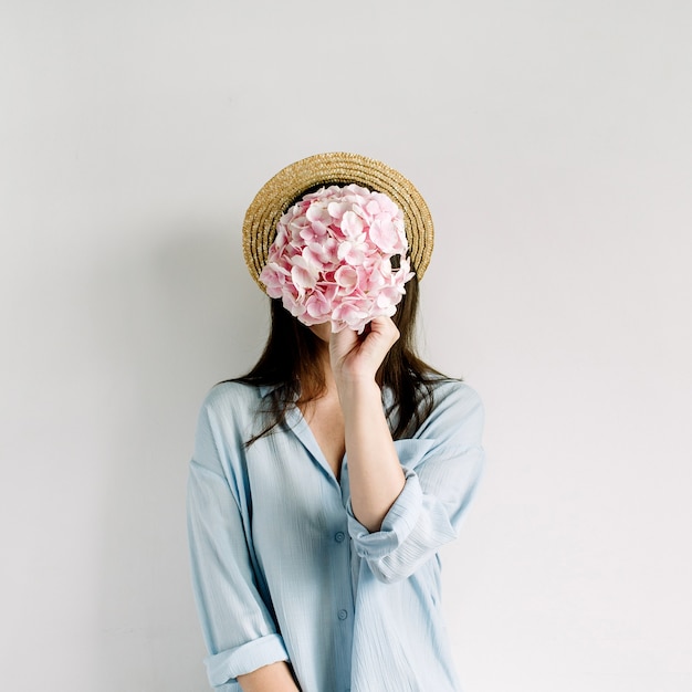 De jonge vrouw houdt het roze boeket van de hortensiabloem op witte oppervlakte