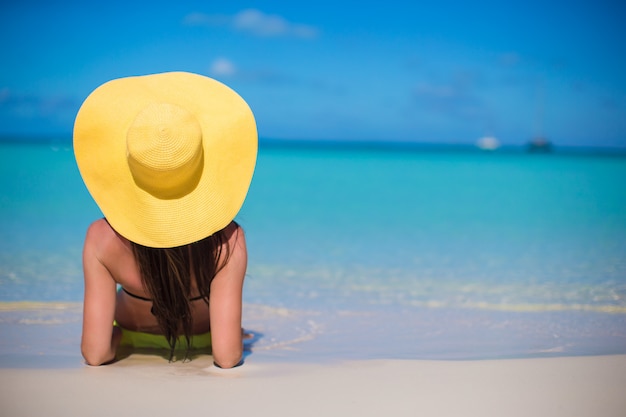 De jonge vrouw in hoed op het strand geniet van Caraïbische vakantie