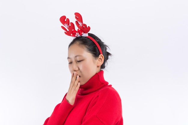 De jonge vrouw in kersttrui en muts op de witte achtergrond