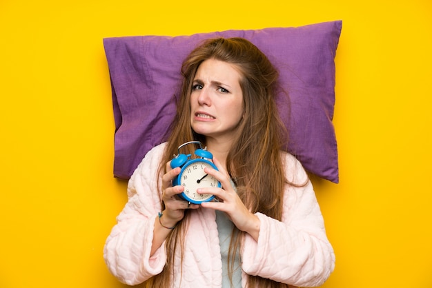 De jonge vrouw in peignoir in een bed beklemtoonde het houden van uitstekende klok