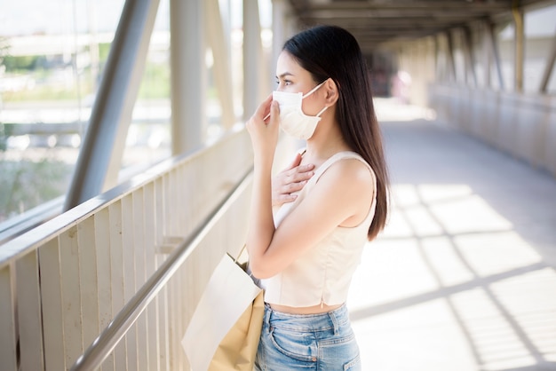 De jonge vrouw met gezichtsmasker bevindt zich openluchtstad