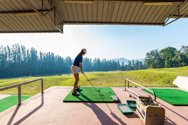 De jonge vrouw oefent haar golfschommeling op drijfwaaier