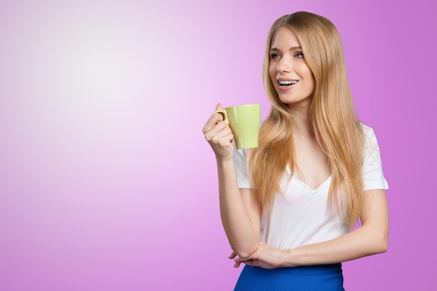 De jonge vrouw op studioachtergrond drinkt koffie of thee