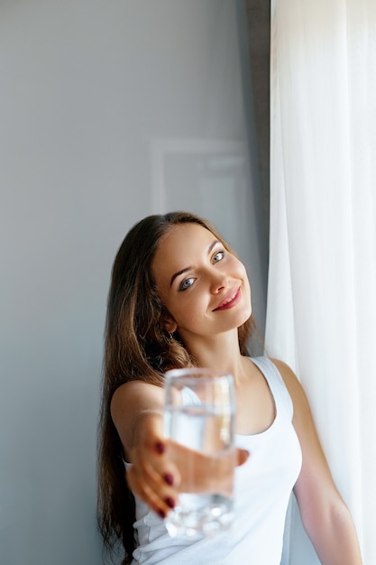 De jonge vrouw van de close-up toont glas water