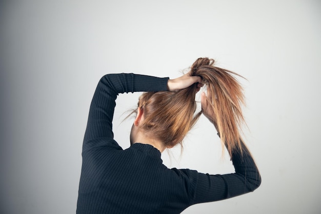 De jonge vrouw verzamelt haar in een paardenstaart.