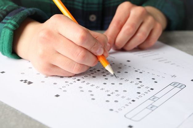 De jonge vrouw vult testblad op grijze lijst, omhoog sluit