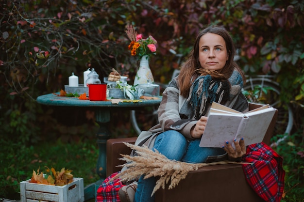 De jonge vrouw zit buiten stoel met een boek