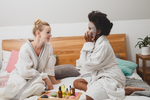 De jonge vrouwen met maskers zitten in de spa