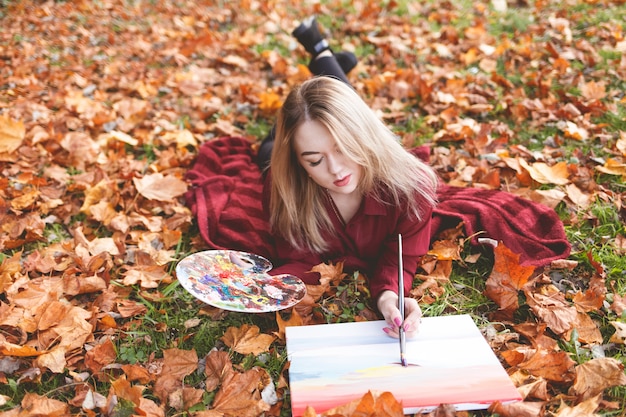 Foto de jonge vrouwenkunstenaar ontspant in het park voor haar favoriete hobby.