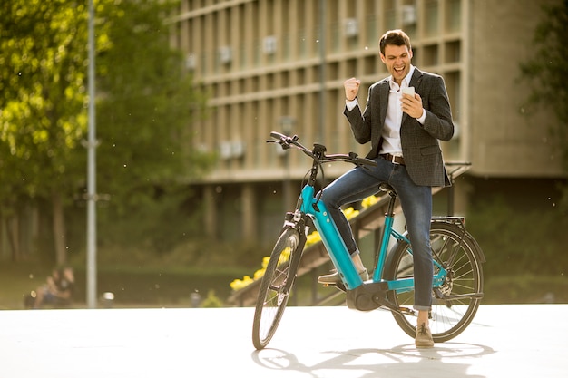 De jonge zakenman op de ebike ontving gretnieuws via de mobiele telefoon