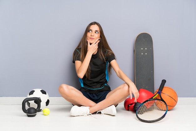 De jonge zitting van de sportvrouw op de vloer die een idee denkt