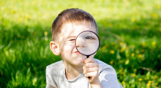 De jongen bekijkt de bloem door een vergrootglas