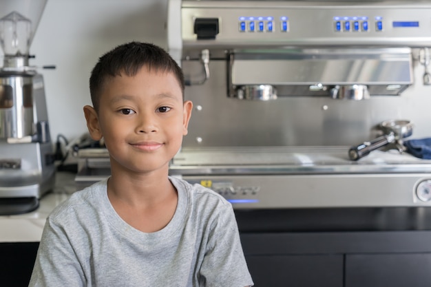 De jongen die bij koffiewinkel zit met Koffiemachine