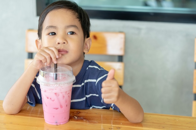 de jongen die een roze melk drinkt