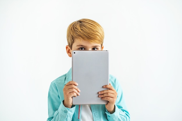 De jongen die een tablet op de witte achtergrond houdt