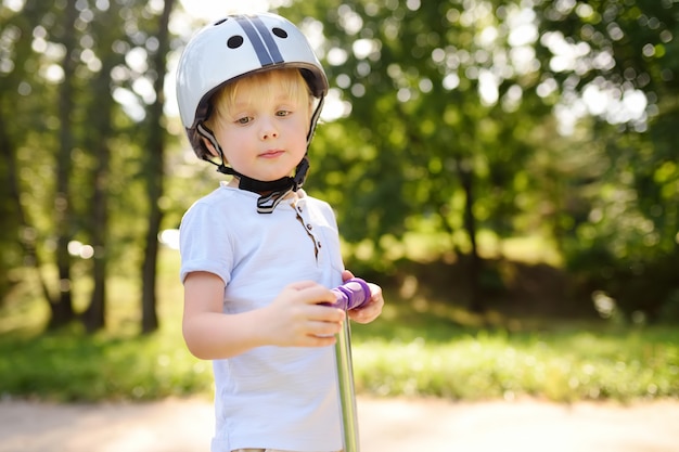 De jongen die van de peuter in veiligheidshelm scooter leert te berijden