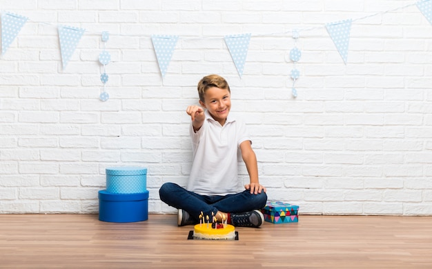 De jongen die zijn verjaardag met een cake viert richt vinger op u