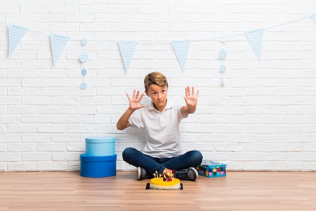 De jongen die zijn verjaardag viert met een cake is een beetje nerveus en bang