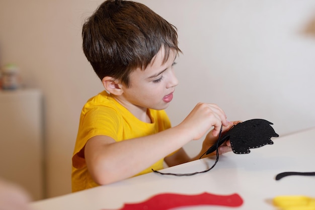 de jongen doet handwerk Een zacht stuk speelgoed naaien van vilten handen close-up Tijdverdrijf thuis