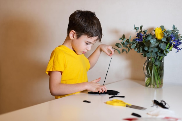 De jongen doet handwerk een zacht stuk speelgoed naaien van vilten handen close-up tijdverdrijf thuis