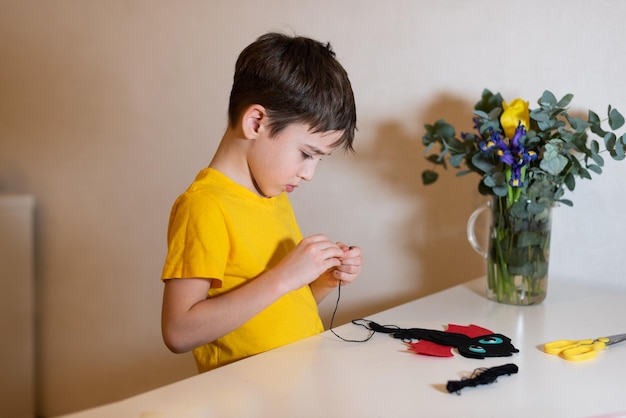 de jongen doet handwerk Een zacht stuk speelgoed naaien van vilten handen close-up Tijdverdrijf thuis