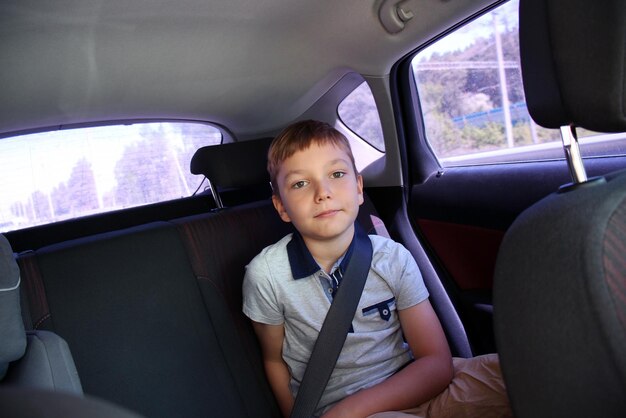 De jongen draagt een veiligheidsgordel en zit op de achterstoel van de auto Closeup portret