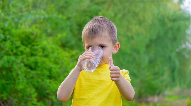 De jongen drinkt water uit een glas zuiver water zomer