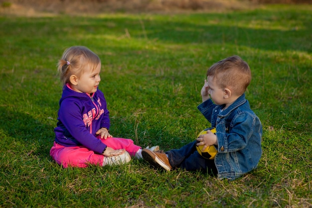 De jongen en het meisje van twee jaar spelen in het voorjaar op het glas