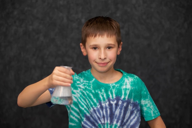 De jongen houdt een glazen chemische kolf in zijn hand