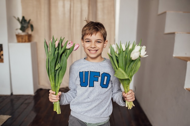 De jongen lacht vurig met een boeket bloemen