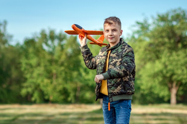 De jongen lanceert een speelgoedvliegtuig.